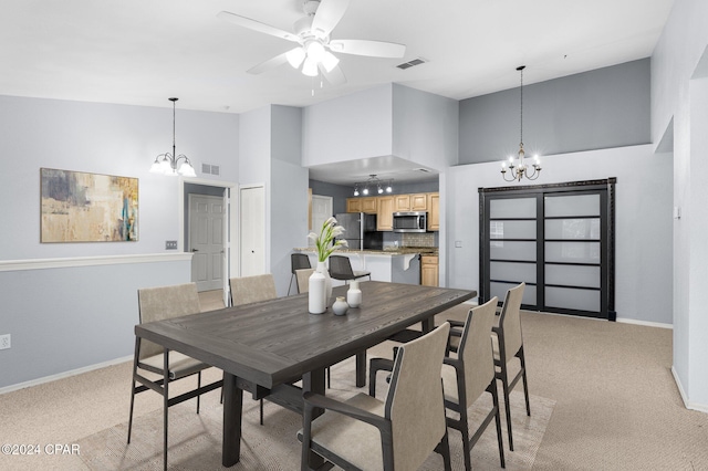 carpeted dining space with a high ceiling and ceiling fan with notable chandelier