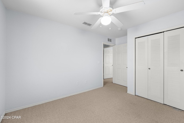 unfurnished bedroom with ceiling fan, light carpet, and a closet