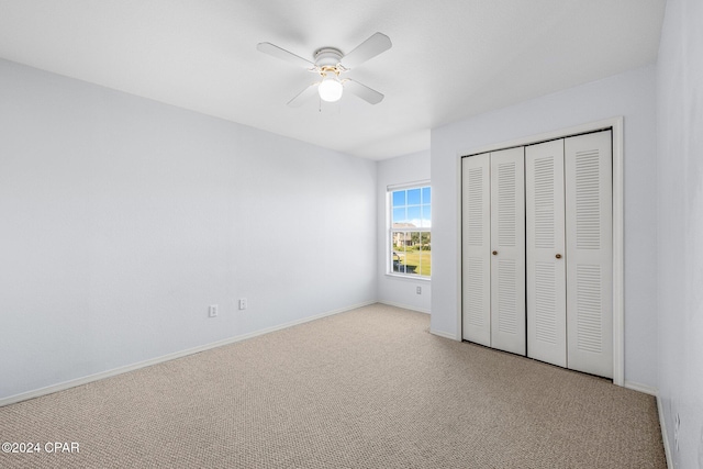 unfurnished bedroom featuring ceiling fan, light colored carpet, and a closet