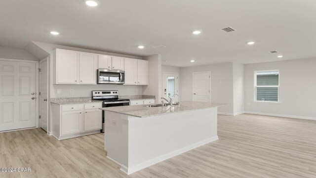 kitchen with appliances with stainless steel finishes, sink, light hardwood / wood-style flooring, white cabinets, and an island with sink