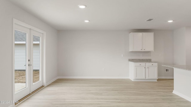 unfurnished dining area featuring french doors and light hardwood / wood-style flooring