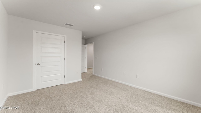 unfurnished bedroom featuring light colored carpet and a closet