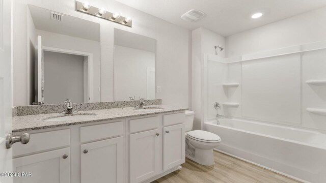 full bathroom featuring hardwood / wood-style floors, vanity, toilet, and shower / bath combination