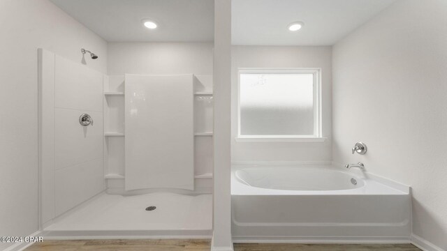 bathroom featuring hardwood / wood-style floors and plus walk in shower