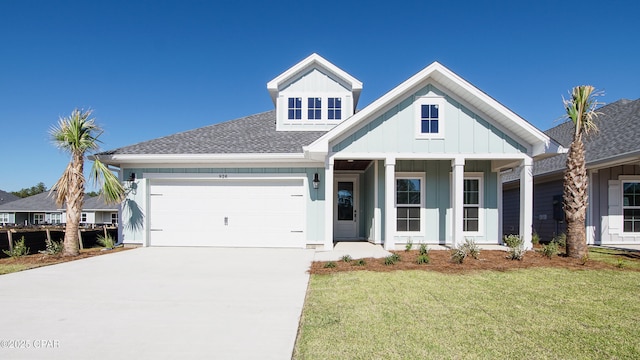 view of front of house featuring driveway, board and batten siding, a front yard, a shingled roof, and a garage