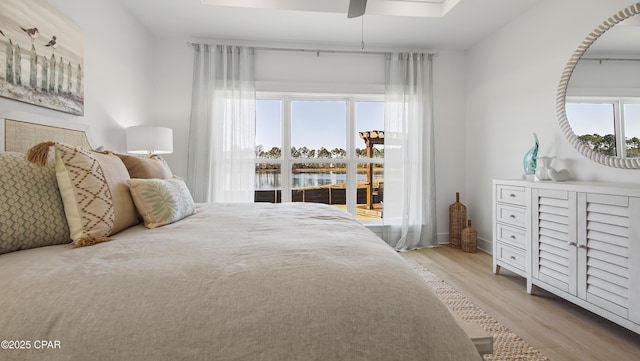 bedroom with a water view, ceiling fan, and light hardwood / wood-style floors