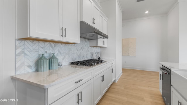 kitchen with stainless steel appliances, light stone countertops, light wood-type flooring, and white cabinets