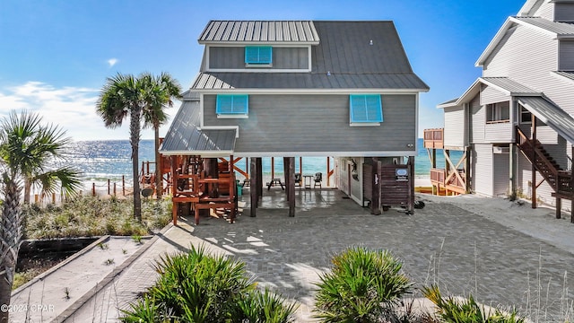 back of property featuring a water view, a beach view, and a carport