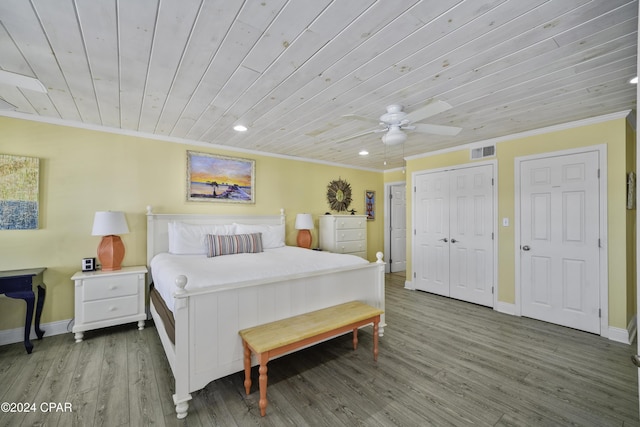 bedroom featuring ceiling fan, wood-type flooring, wood ceiling, two closets, and ornamental molding