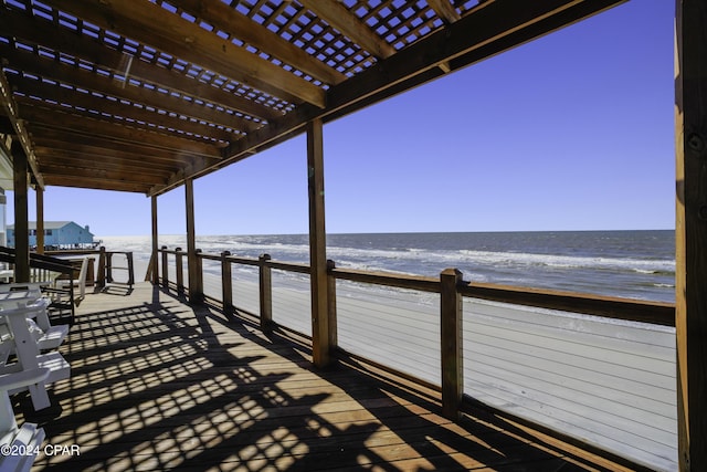 wooden deck featuring a pergola, a water view, and a beach view