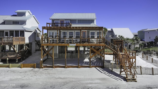 snow covered house featuring a wooden deck and a balcony