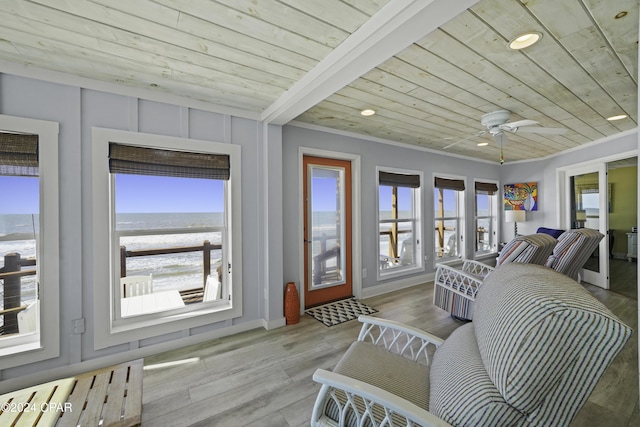 sunroom / solarium with a water view, wood ceiling, and a wealth of natural light