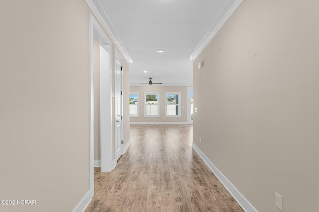 corridor with light hardwood / wood-style floors and ornamental molding