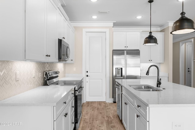 kitchen featuring appliances with stainless steel finishes, sink, light hardwood / wood-style flooring, white cabinetry, and hanging light fixtures