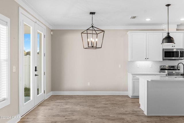 kitchen with white cabinets, appliances with stainless steel finishes, plenty of natural light, and hanging light fixtures