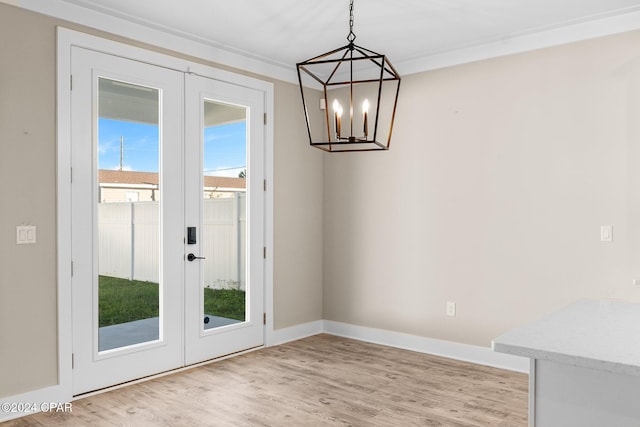 unfurnished dining area with light wood-type flooring, ornamental molding, and french doors