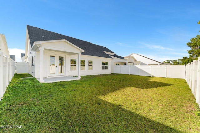 rear view of property with french doors and a lawn