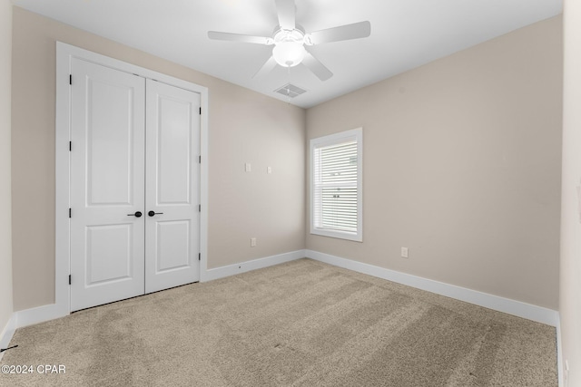 unfurnished bedroom with ceiling fan, light carpet, and a closet