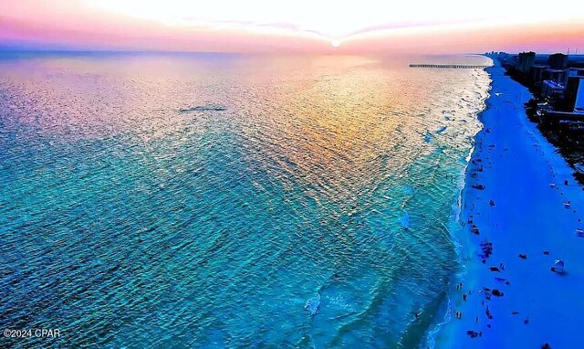 aerial view at dusk with a beach view and a water view