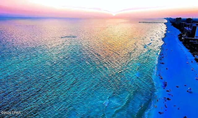 aerial view at dusk with a water view and a view of the beach