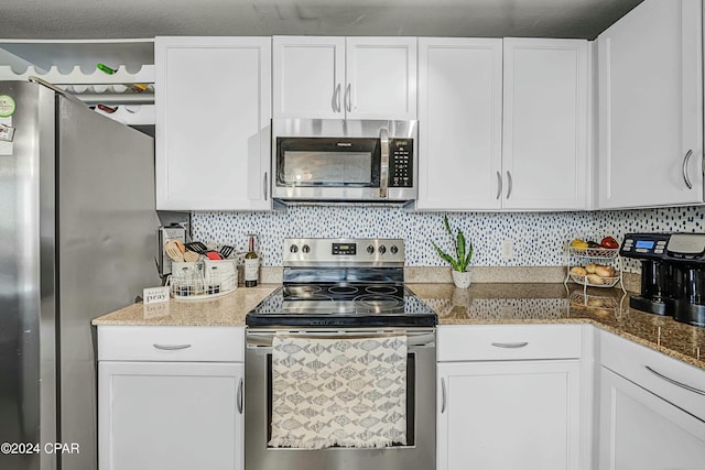 kitchen with decorative backsplash, a textured ceiling, stainless steel appliances, stone counters, and white cabinetry