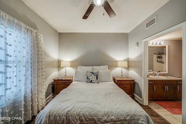 bedroom with ensuite bath, ceiling fan, light hardwood / wood-style flooring, and sink