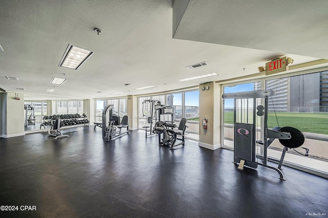 gym with a wall of windows and a textured ceiling