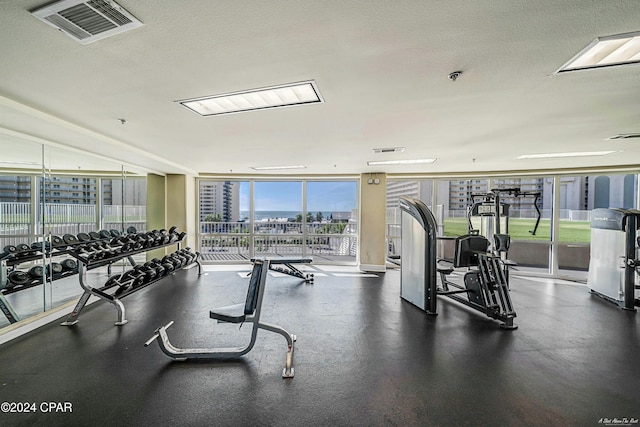 gym featuring a wall of windows and a textured ceiling