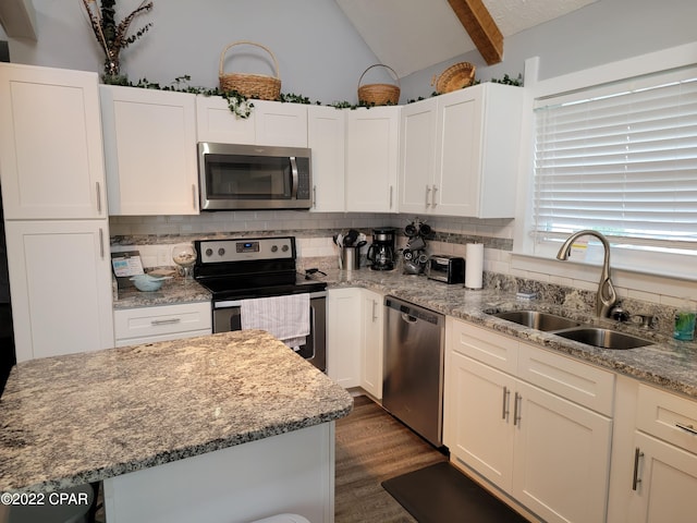 kitchen with light stone counters, stainless steel appliances, dark wood-type flooring, sink, and lofted ceiling with beams