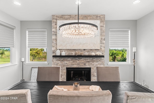 living room with a wealth of natural light, a fireplace, and a notable chandelier