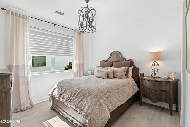 bedroom with light hardwood / wood-style flooring and a notable chandelier