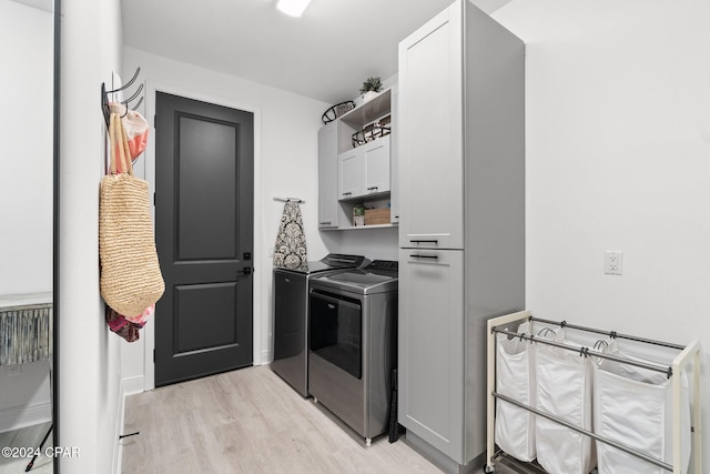 clothes washing area with cabinets, separate washer and dryer, and light hardwood / wood-style flooring