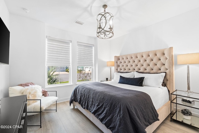 bedroom with light wood-type flooring and an inviting chandelier