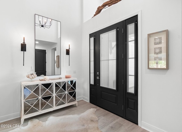 entrance foyer featuring light hardwood / wood-style floors, a high ceiling, and an inviting chandelier