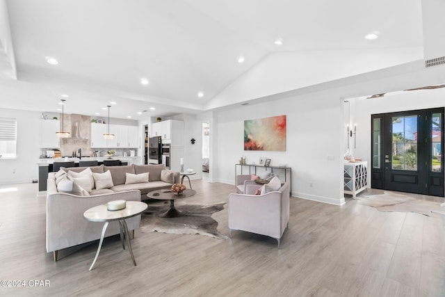 living room featuring light hardwood / wood-style flooring, high vaulted ceiling, and sink