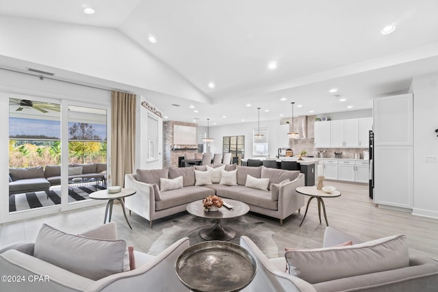 living room featuring light hardwood / wood-style flooring, high vaulted ceiling, and ceiling fan