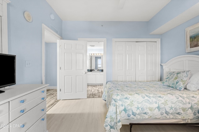 bedroom featuring ceiling fan, light hardwood / wood-style floors, ensuite bath, and a closet