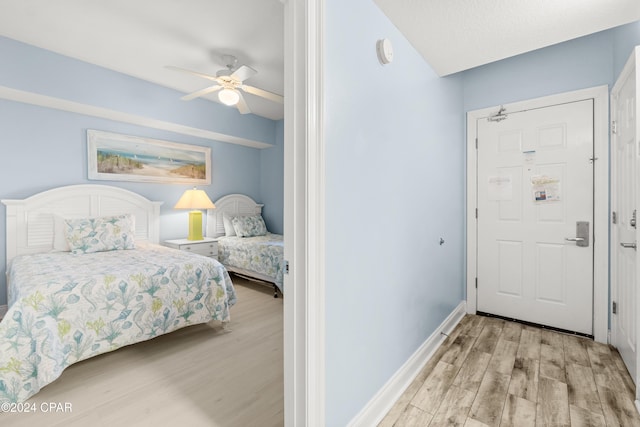 bedroom with ceiling fan, light hardwood / wood-style flooring, and a textured ceiling