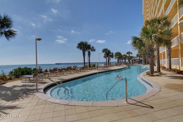 view of pool with a patio and a water view