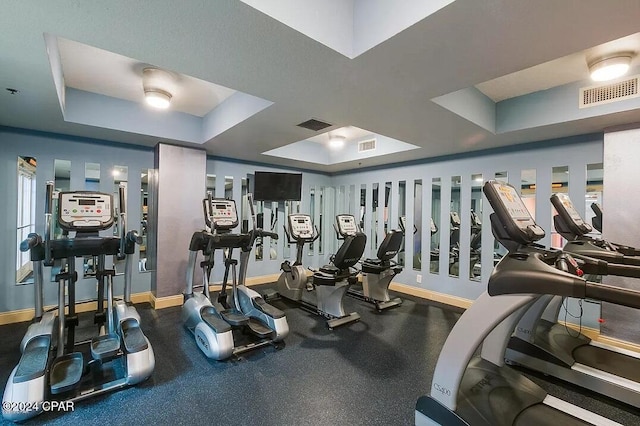 workout area with a tray ceiling and plenty of natural light