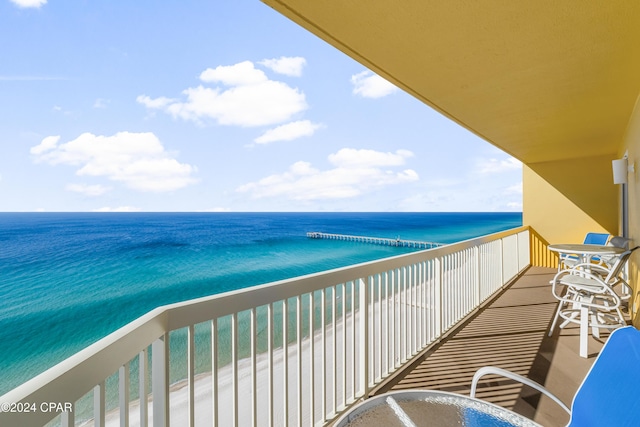 balcony with a water view and a view of the beach