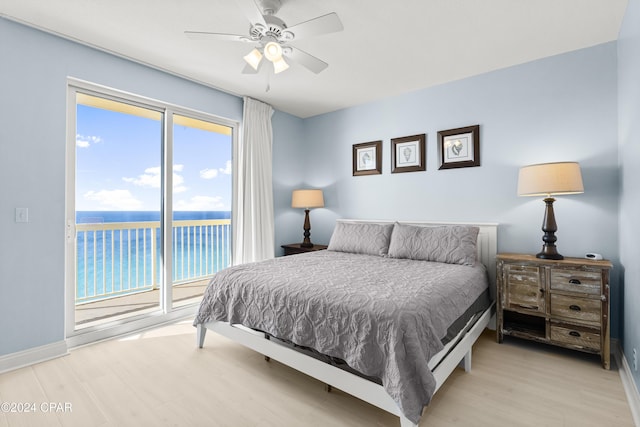 bedroom featuring access to exterior, ceiling fan, a water view, and multiple windows