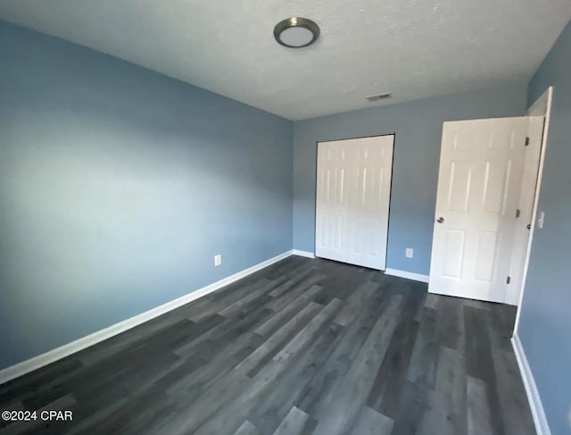 unfurnished bedroom with a closet and dark hardwood / wood-style flooring