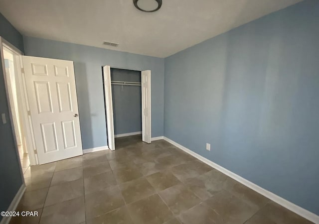 unfurnished bedroom featuring dark tile patterned flooring and a closet