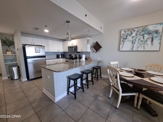 kitchen featuring white cabinets, decorative light fixtures, stainless steel appliances, and kitchen peninsula