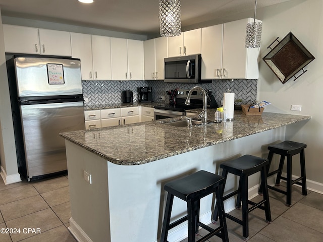 kitchen featuring a kitchen breakfast bar, white cabinetry, kitchen peninsula, and appliances with stainless steel finishes