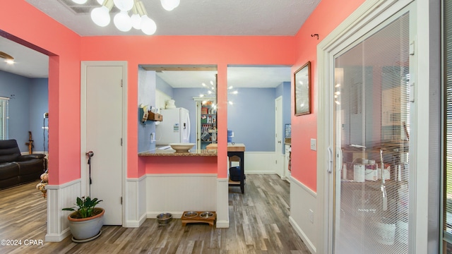 hallway with a chandelier, a textured ceiling, and hardwood / wood-style flooring