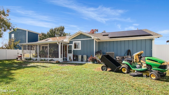 rear view of house featuring solar panels, a lawn, and a sunroom