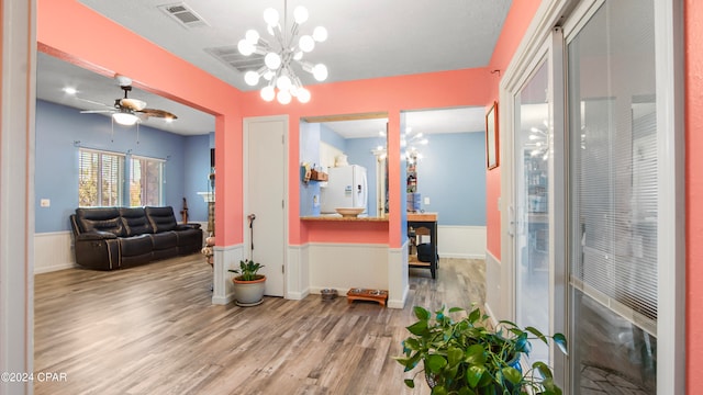 interior space with ceiling fan with notable chandelier and light hardwood / wood-style floors