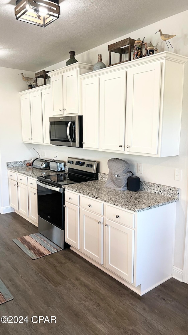 kitchen featuring white cabinets, appliances with stainless steel finishes, dark hardwood / wood-style flooring, and a textured ceiling